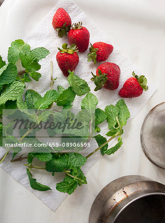 Freshly washed strawberries and mint sprigs on kitchen roll