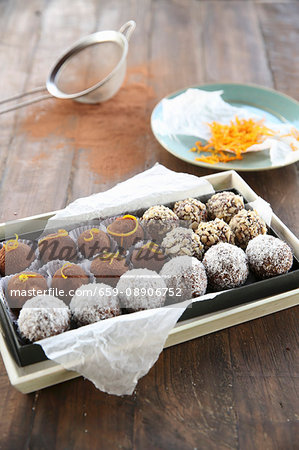 Assorted bliss ball truffles on paper in a chocolate box