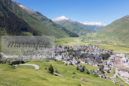 The alpine village of Andermatt surrounded by green meadows, and snowy peaks in the background, Canton of Uri, Switzerland, Europe