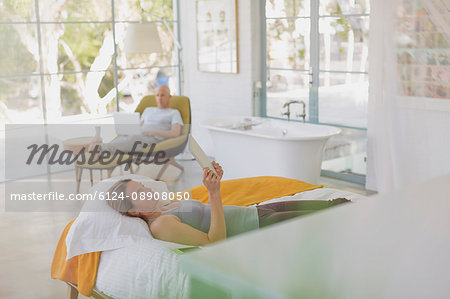 Couple relaxing, using laptop and digital tablet in luxury hotel bedroom