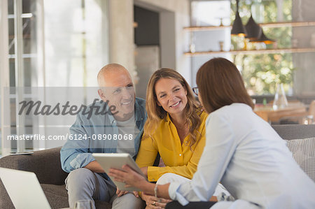 Financial advisor with digital tablet meeting with couple in living room