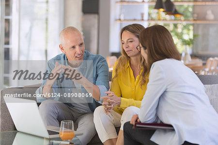 Financial advisor with laptop meeting with couple in living room