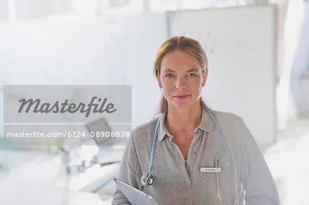 Portrait confident female doctor with digital tablet in doctor’s office