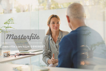 Female doctor talking with male patient in doctor’s office