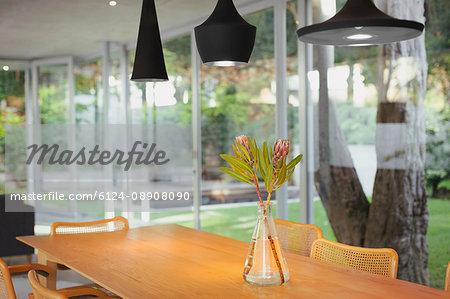 Modern black pendant lights hanging over bouquet on dining room table