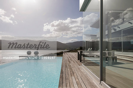 Sunny, tranquil modern luxury home showcase exterior with infinity pool and ocean view Sunny, tranquil modern luxury home showcase exterior with infinity pool and ocean view