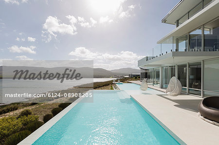 Sunny, tranquil modern luxury home showcase exterior with infinity pool and ocean view Sunny, tranquil modern luxury home showcase exterior with infinity pool and ocean view