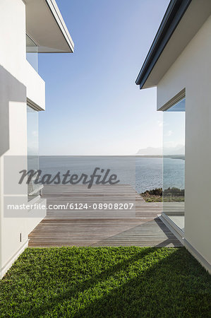 Modern home showcase exterior courtyard with sunny, tranquil ocean view Modern home showcase exterior courtyard with sunny, tranquil ocean view
