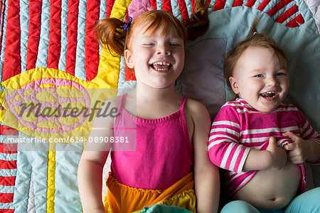 Portrait of two young sisters lying on blanket, laughing