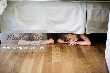 Boy and girl hiding under bed