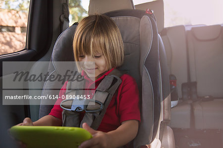 Girl in car safety seat looking at digital tablet