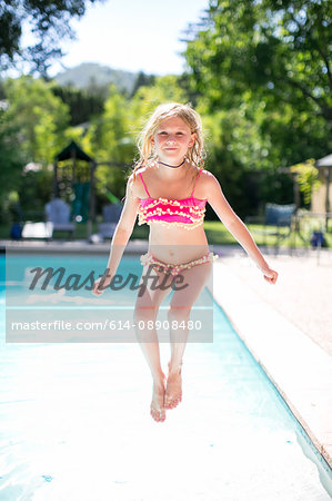 Portrait of girl jumping into outdoor swimming pool