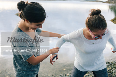 Woman helping sister on shingle beach, Maine, USA