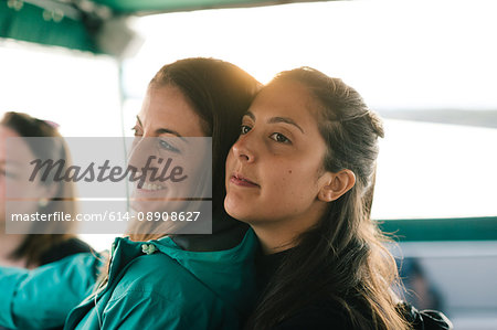 Three adult sisters looking out from boat on coast of Maine, USA