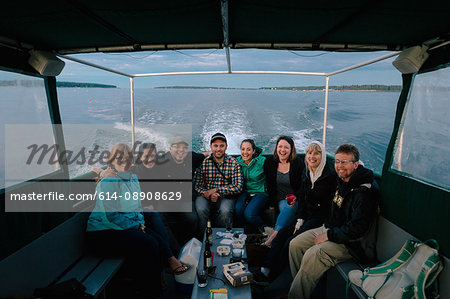 Portrait of adult family sitting in boat at sea near coast of Maine, USA