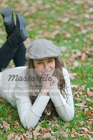 Portrait of a content woman lying down in the park and smiling at camera
