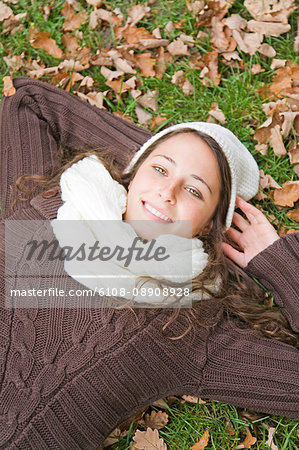 Portrait of a content woman lying down in the park smiling at camera