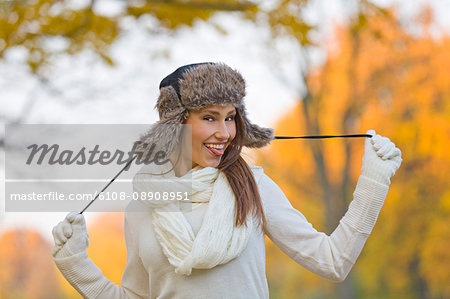 Portrait of a playful beautiful woman in the park in Autumn smiling at camera