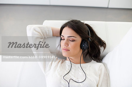 Pretty woman with headphones on the sofa