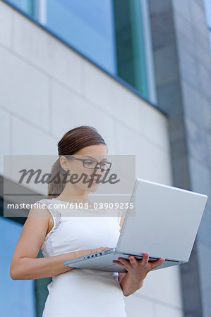 Pretty businesswoman with computer in front of a building