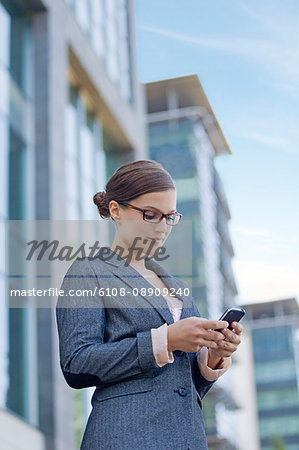 Businesswoman walking with mobile in front of the office