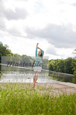 Pretty woman stretching by a lake