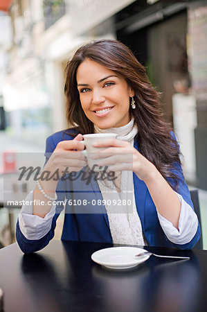 Pretty woman enjoying a coffee in a Cafe, smiling at camera