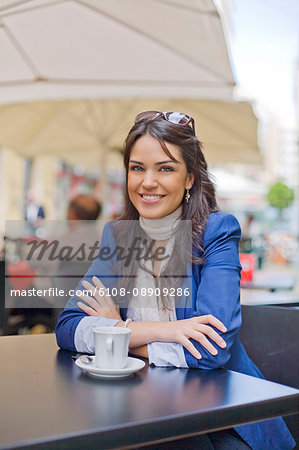 Portrait of a pretty brunette woman having a coffee outdoor smiling