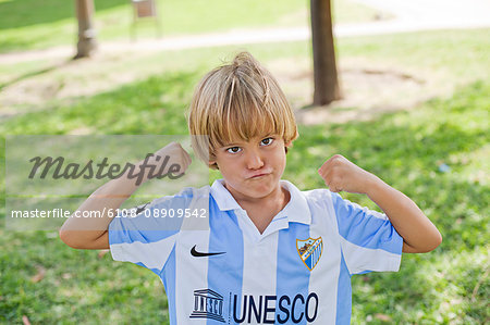 Playful blond boy in park with football t-shirt