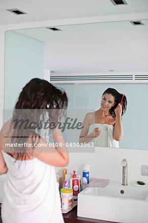 Brunette woman brushing her hair in front of the mirror