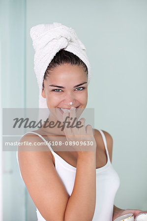 Brunette woman applying anti wrinkle cream after the shower