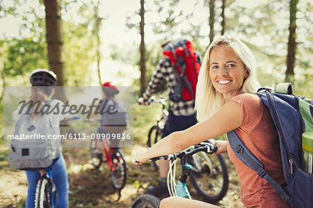 Portrait smiling mother mountain biking with family in woods