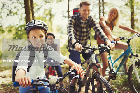 Portrait smiling girl mountain biking with family in woods