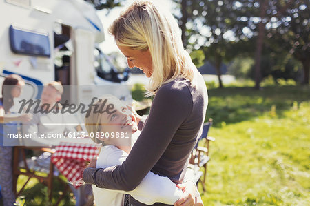 Affectionate mother and daughter hugging outside sunny motor home