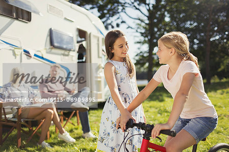 Sisters with bicycle outside sunny motor home