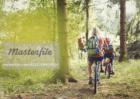 Family mountain biking on trail in woods