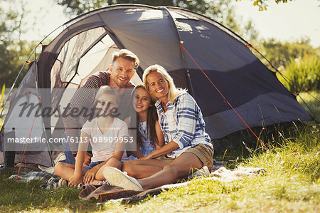 Portrait smiling family relaxing outside sunny campsite tent