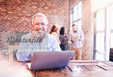 Portrait smiling businessman working at laptop