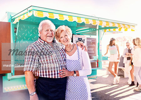 Portrait smiling senior business owners outside sunny food cart