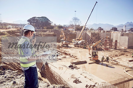 Construction worker foreman using walkie-talkie at sunny construction site
