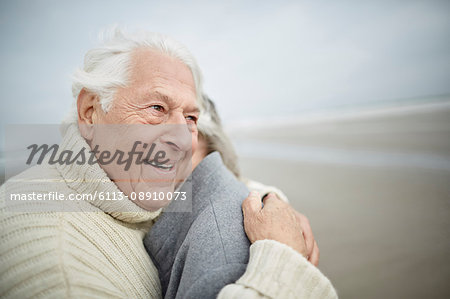 Affectionate senior couple hugging on winter beach