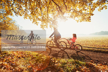 Young family bike riding in sunny autumn park