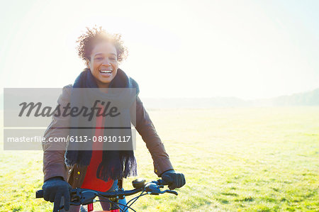 Smiling woman bike riding in sunny park grass