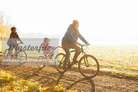 Young family bike riding on path in sunny autumn park