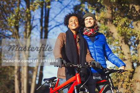 Smiling couple with bicycles in sunny autumn park