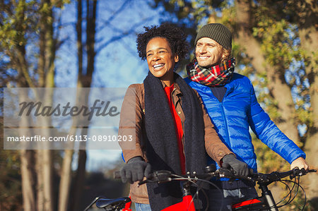 Smiling couple bike riding in sunny autumn park