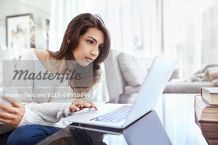 Serious woman using laptop at dining table