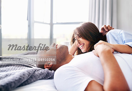 Smiling couple laying and cuddling on bed