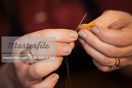 A woman using a needle threaded with cotton thread.