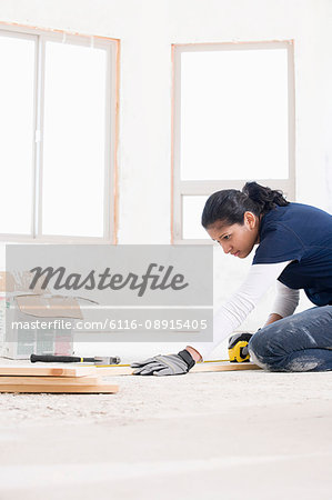 A female builder measuring a plank of wood